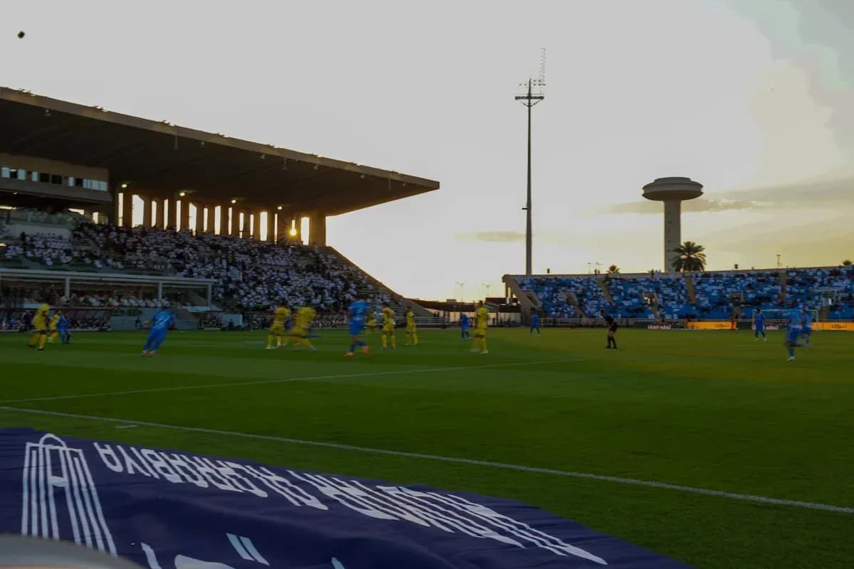 Partido de fútbol en estadio al atardecer