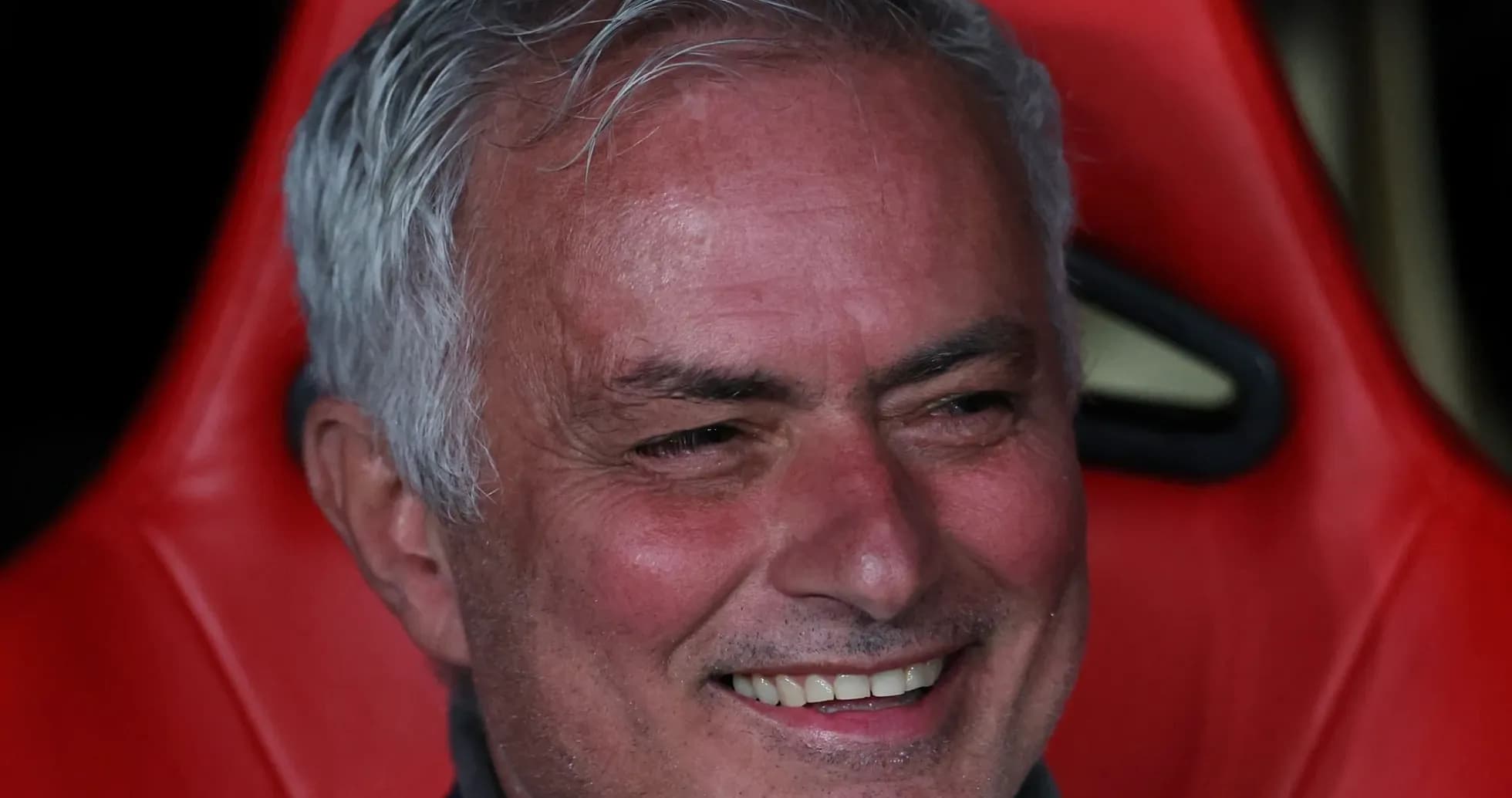 Entrenador sonriendo en el banquillo durante el partido