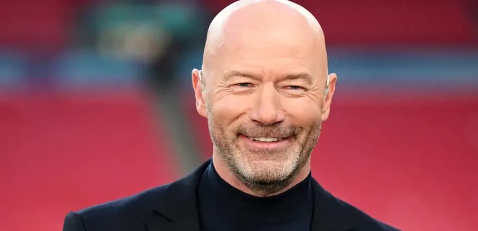 Hombre con chaqueta negra sonriendo en estadio