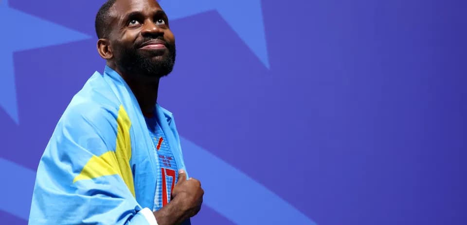 Atleta envuelto en bandera sonriendo en escenario
