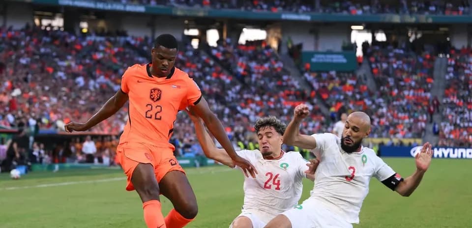 Jugador de Países Bajos driblando entre defensores de Marruecos