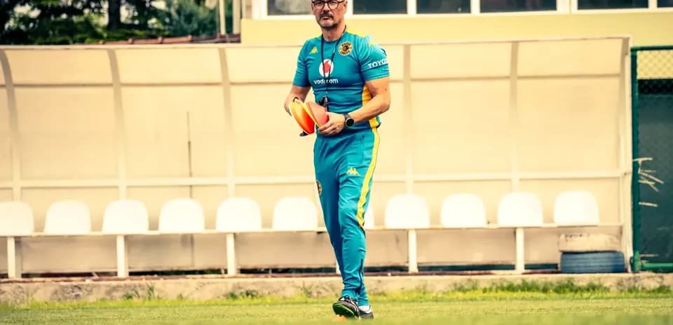 Entrenador sosteniendo conos en campo de entrenamiento