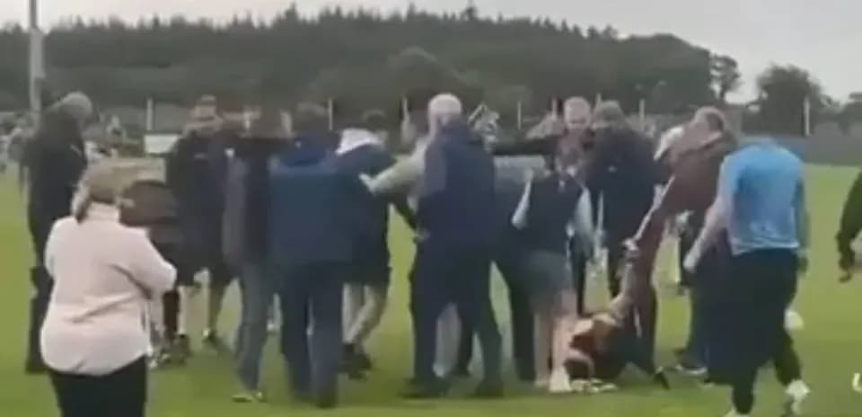 Multitud rodeando a un jugador caído en el campo