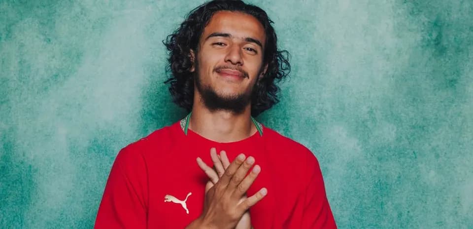 Jugador con camiseta roja sonriendo en fondo verde