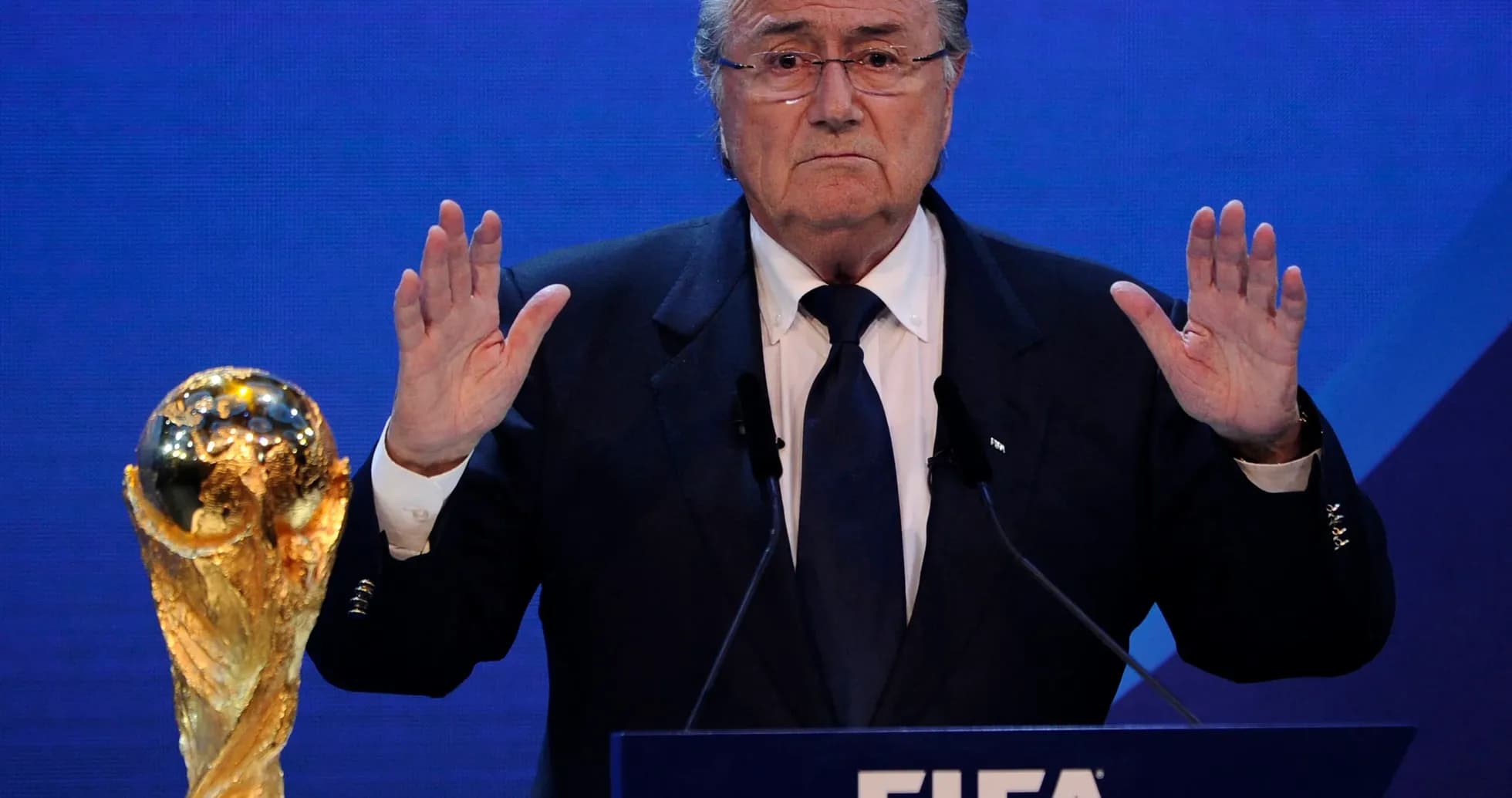 Hombre hablando en podio con trofeo de la FIFA