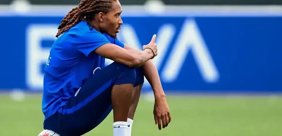 Jugador sentado en el campo con balón de fútbol