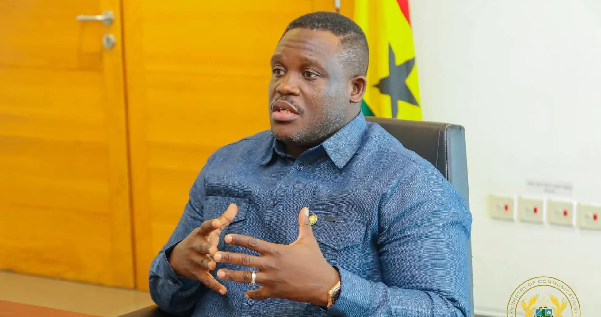 Persona hablando en oficina con bandera de Ghana