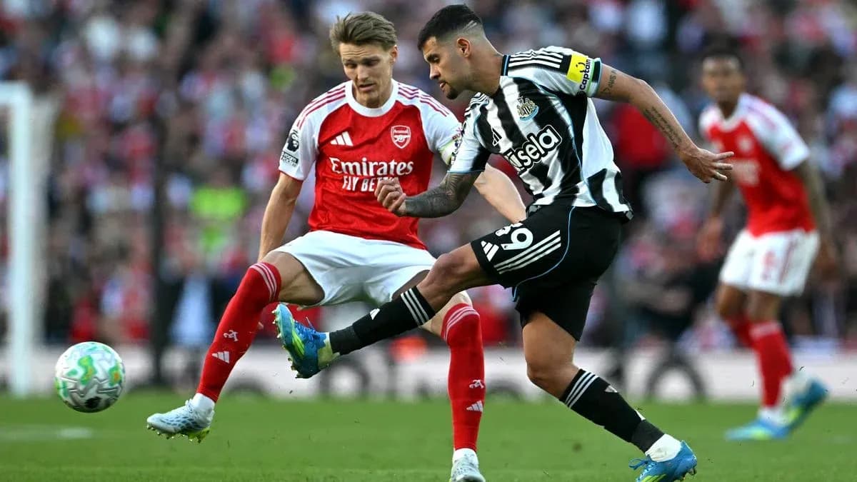 Jugador de Newcastle chutando el balón ante rival de Arsenal
