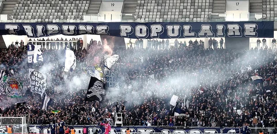 Aficionados con banderas en el estadio lleno de humo