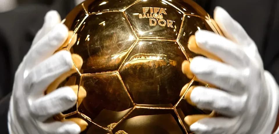 Trofeo Balón de Oro sostenido con guantes blancos