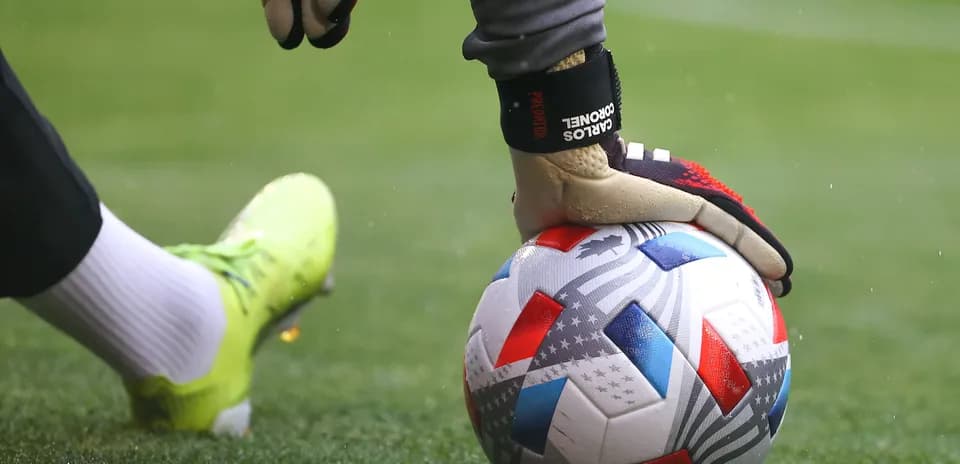 Portero sujetando el balón en el campo de fútbol