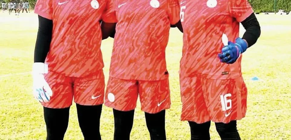 Tres jugadoras de fútbol posando en campo de entrenamiento