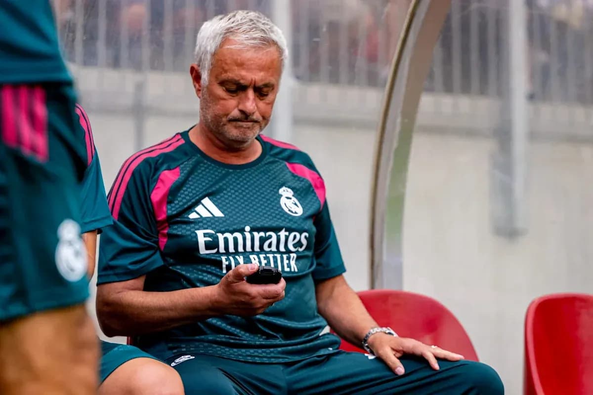 Entrenador sentado en el banquillo revisando su teléfono