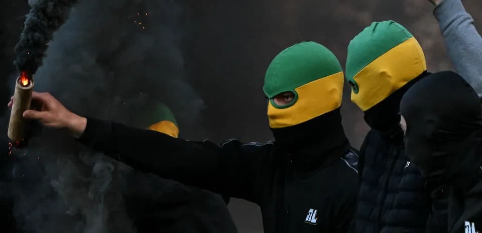 Personas con pasamontañas sosteniendo un artefacto incendiario