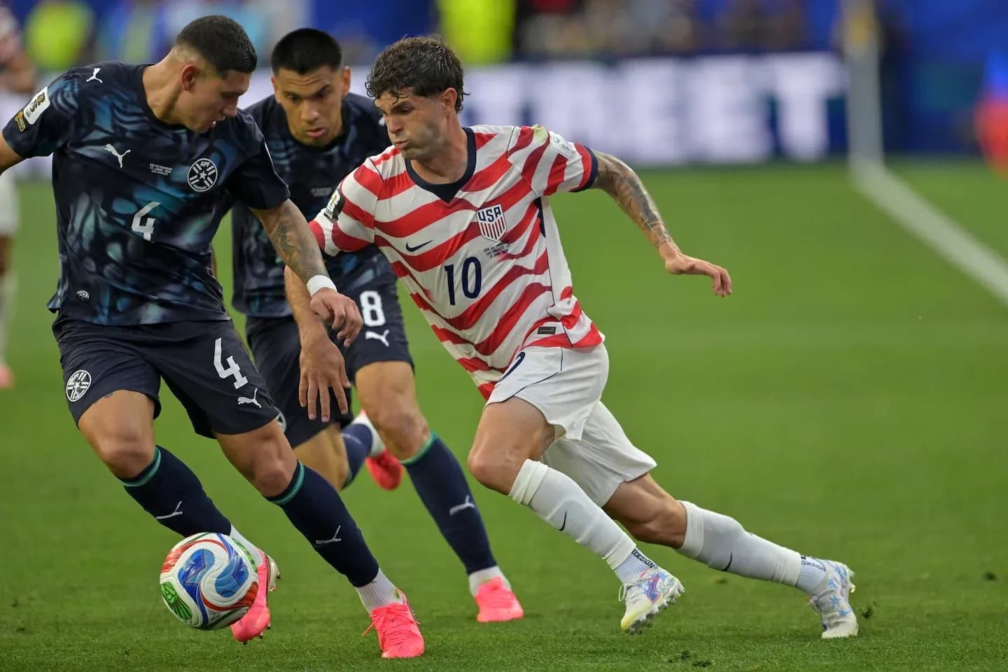 Christian Pulisic dribbling past two defenders