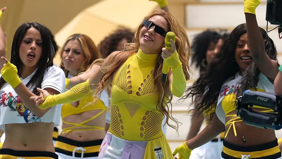 Artista actuando con bailarinas en escenario colorido
