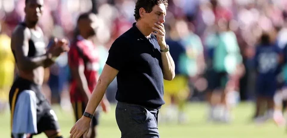 Entrenador caminando tras el partido con jugadores detrás