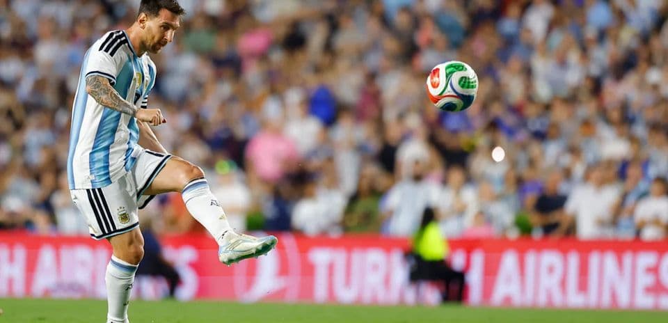 Lionel Messi kicking a soccer ball on the field