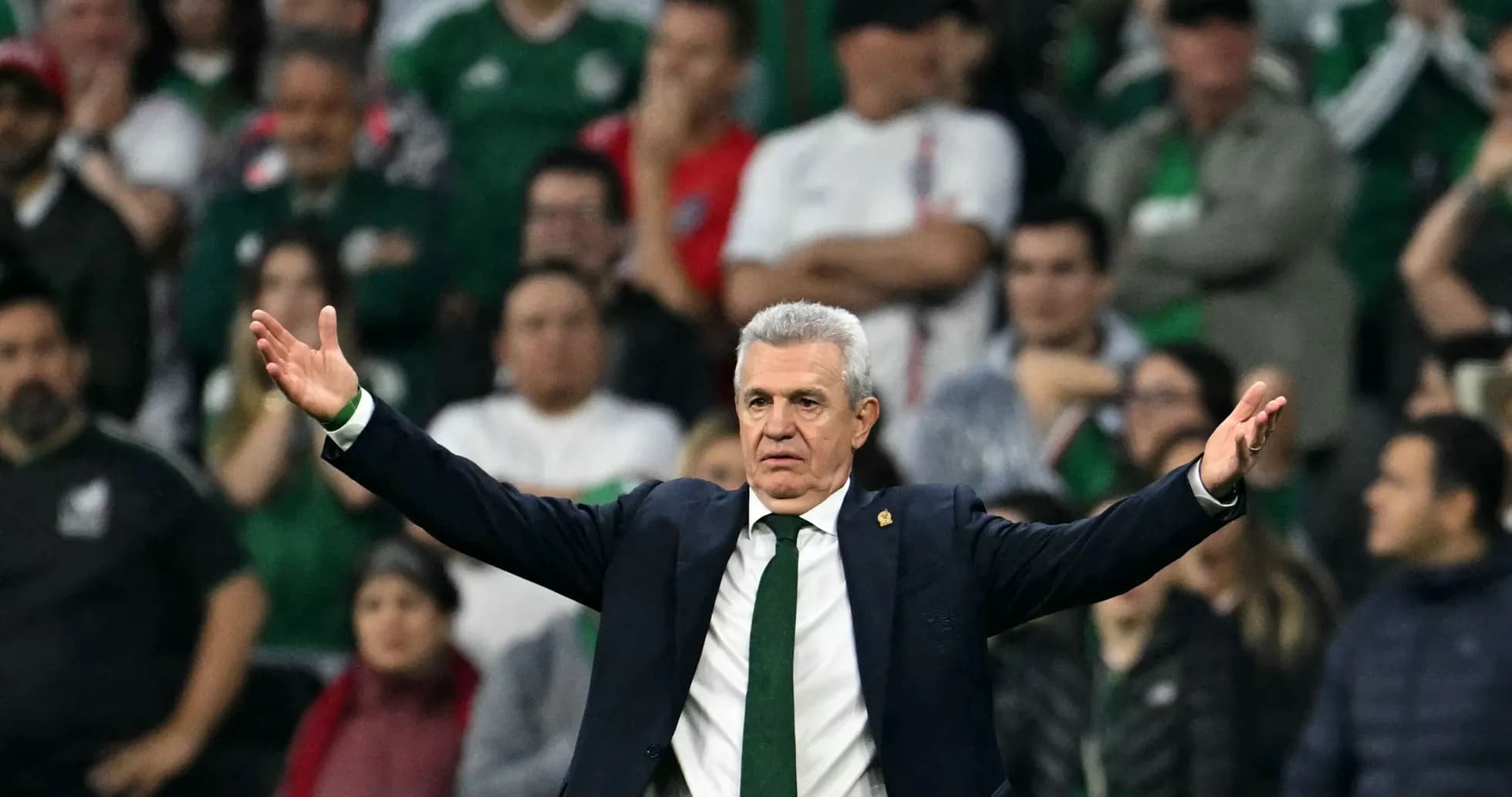Entrenador gesticulando durante partido con aficionados al fondo
