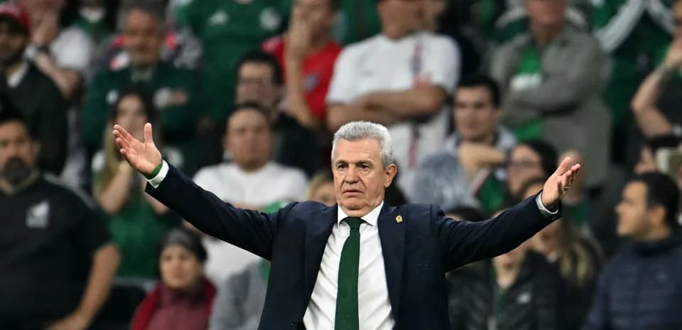 Entrenador gesticulando durante partido con aficionados al fondo