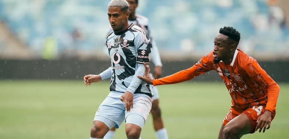 Jugador de fútbol esquivando a oponente en campo lluvioso