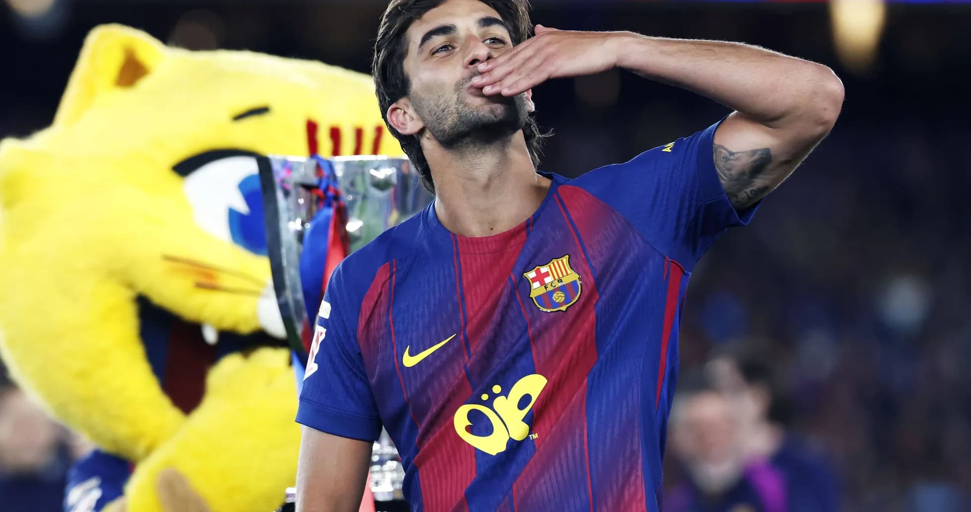 Jugador de Barcelona celebrando con trofeo y mascota
