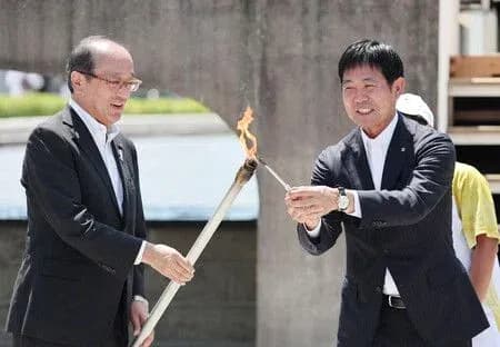 Dos personas encendiendo una antorcha en ceremonia