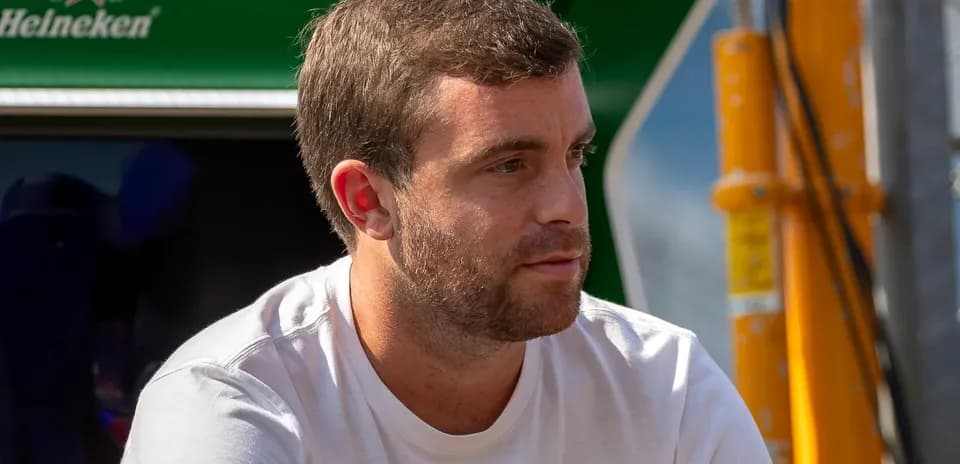 Hombre sentado con camiseta blanca en evento deportivo