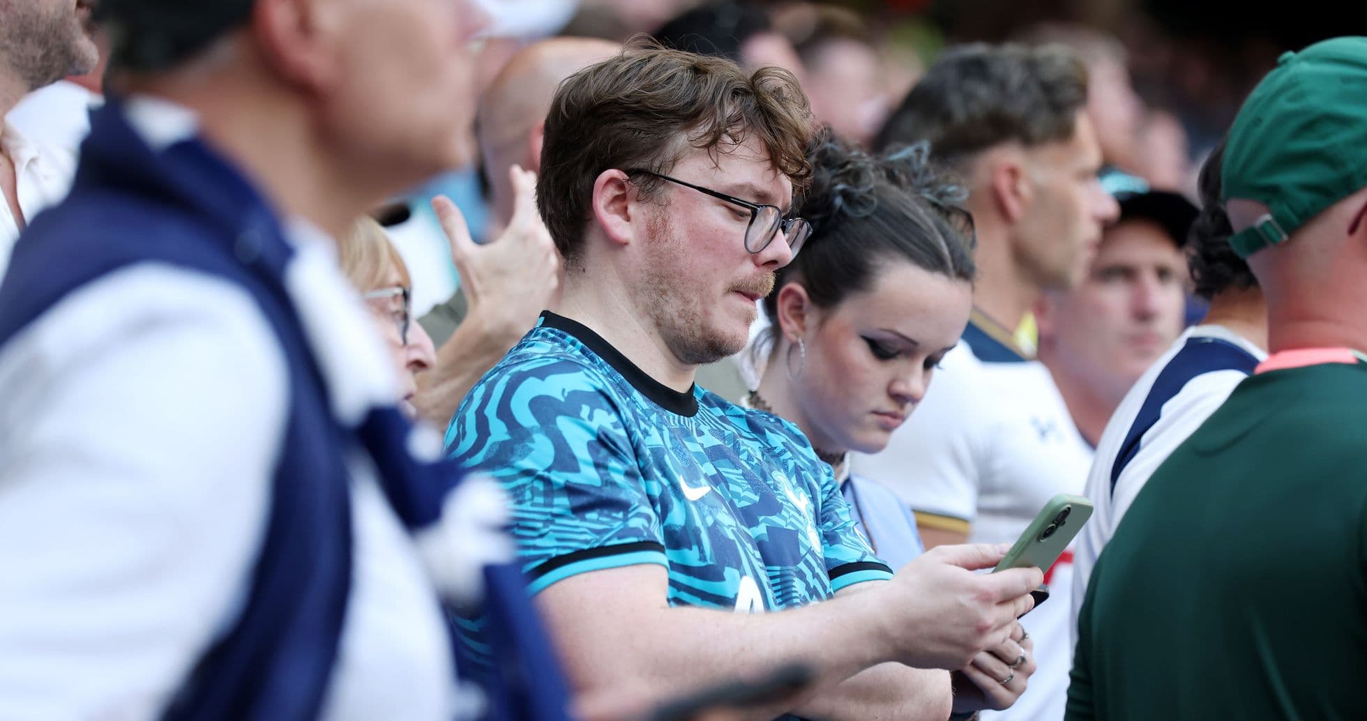 A crowd of fans watching a match, some on phones