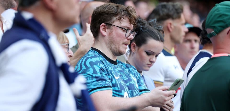 A crowd of fans watching a match, some on phones