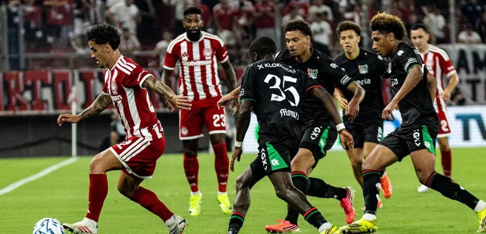 Jugador de Olympiakos esquivando a los defensores de NEC