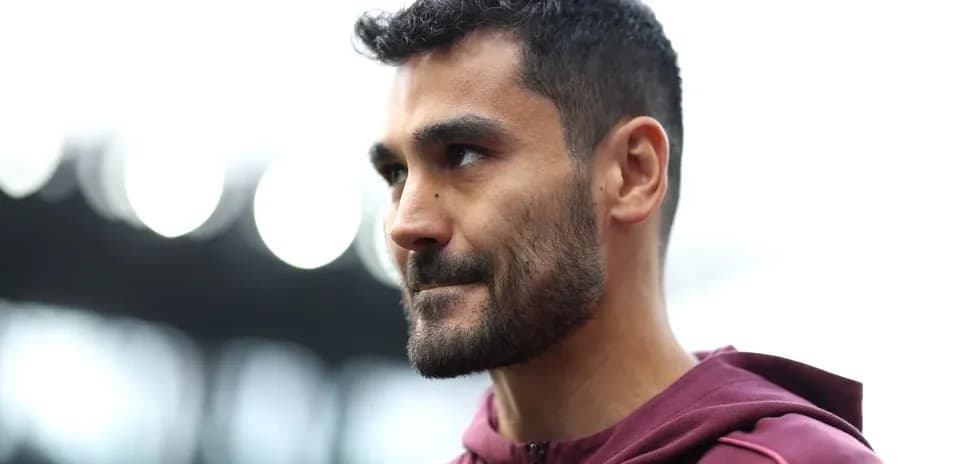 Jugador con chaqueta marrón en estadio