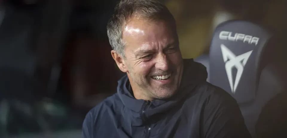 Entrenador sonriendo en el banquillo durante el partido