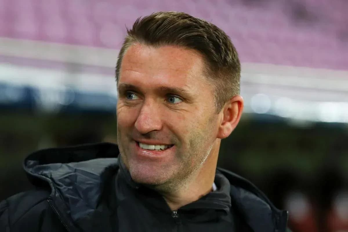 Entrenador sonriendo en el banquillo del estadio