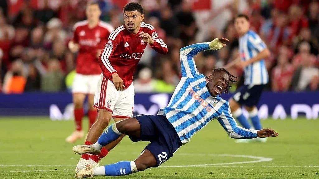 Jugador caído mientras otro lo observa en el partido Jugador caído mientras otro lo observa en el partido