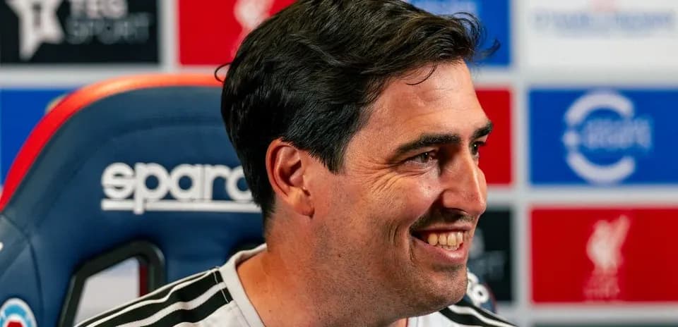 Entrenador sonriendo en conferencia de prensa