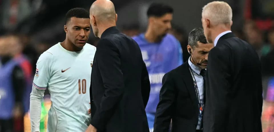 Kylian Mbappé conversando con entrenadores en el campo