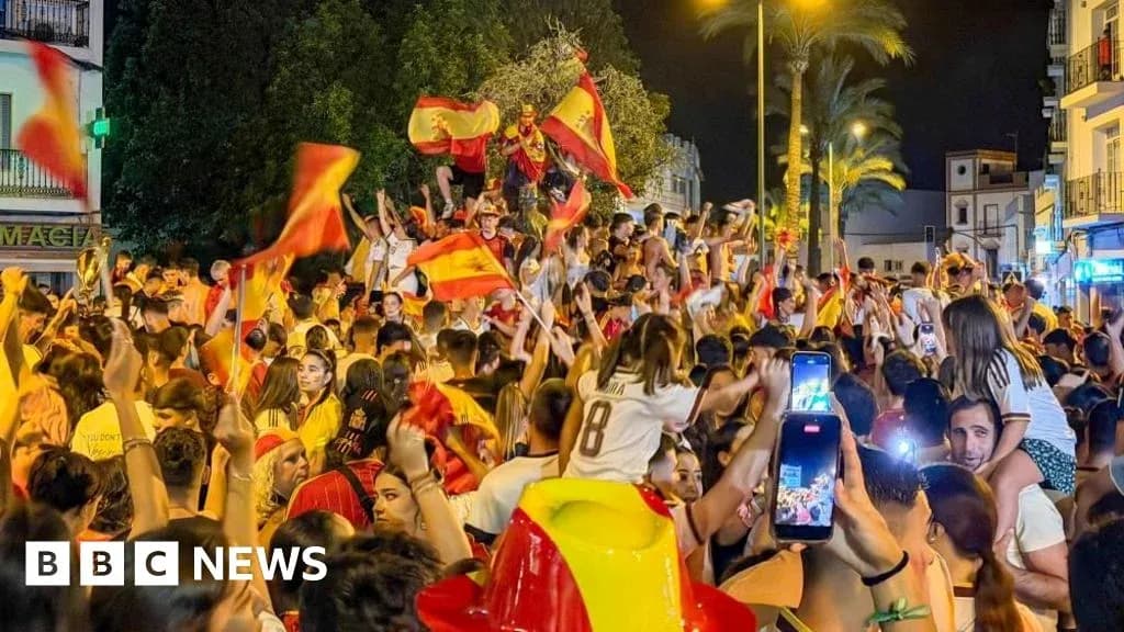 Multitud celebrando con banderas en la calle