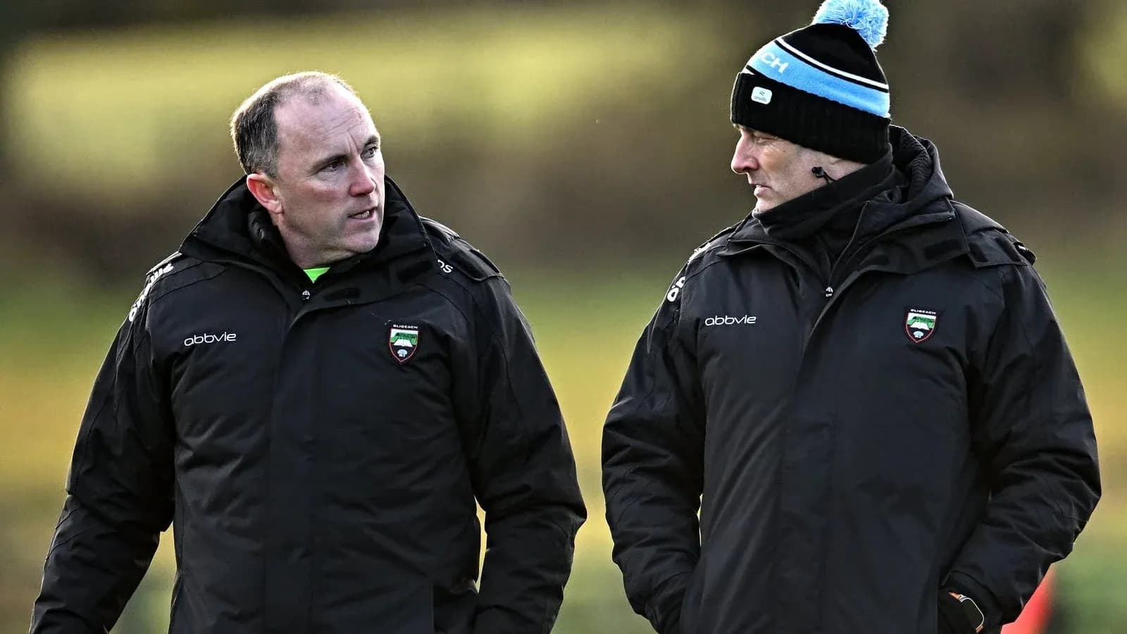 Entrenadores conversando en campo de entrenamiento