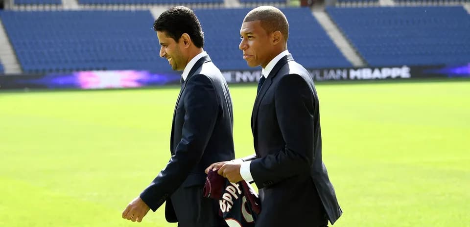 Kylian Mbappé y directivo caminando en el campo