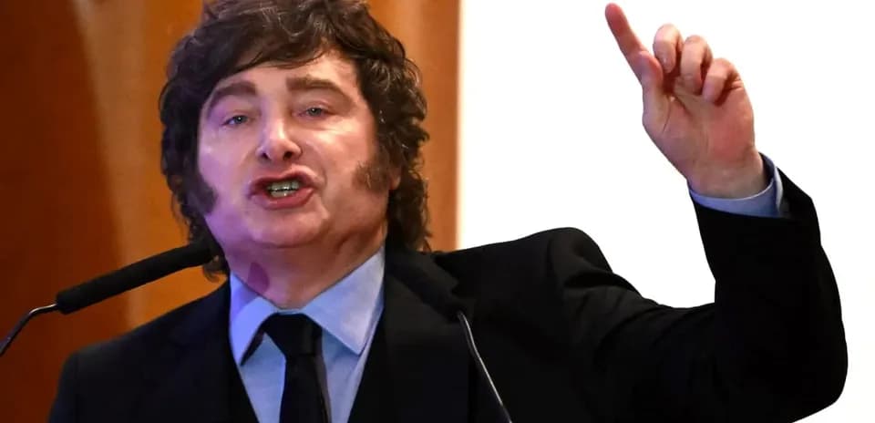 Hombre hablando en un podio con mano levantada