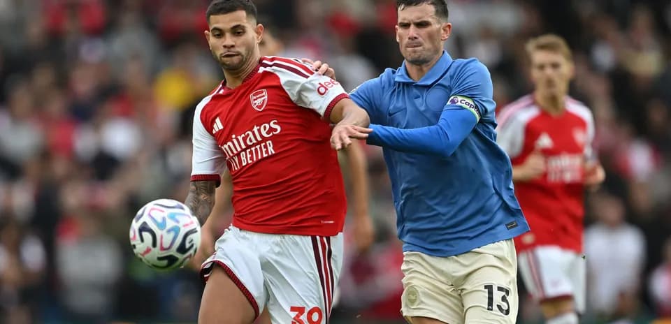 Jugador de Arsenal driblando mientras es marcado