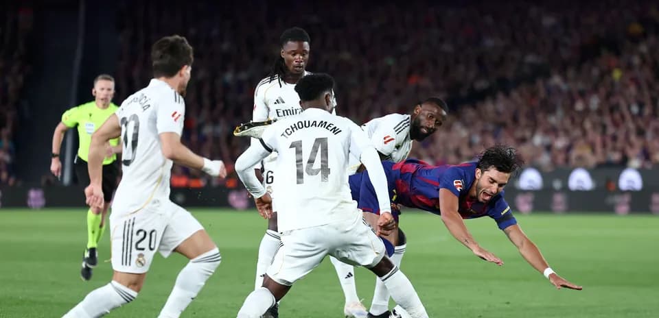 Jugador de Barcelona cayendo entre defensores del Real Madrid