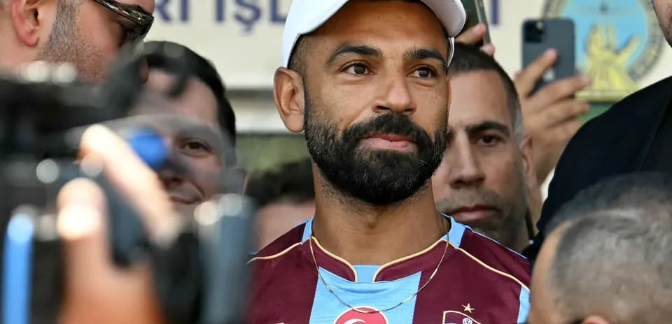 Jugador de fútbol en conferencia de prensa rodeado de aficionados