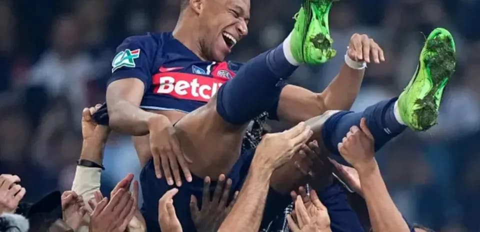 Kylian Mbappé siendo levantado por compañeros de equipo
