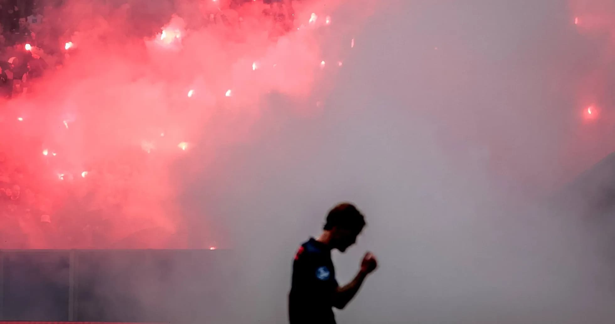Jugador celebrando con humo y bengalas de fondo