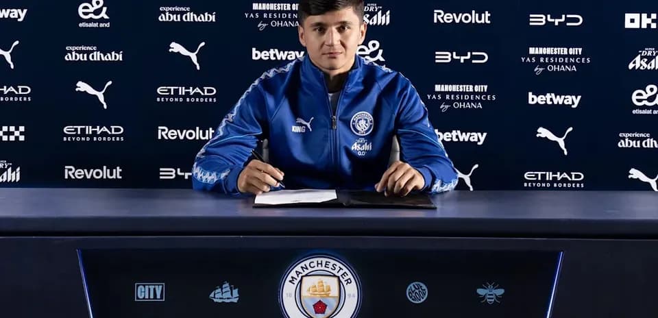 Jugador firmando contrato en mesa de prensa