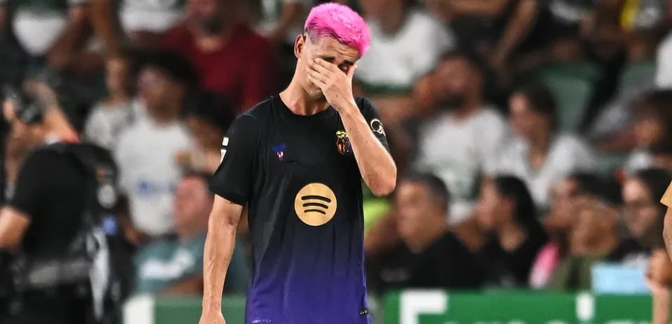 Jugador de fútbol con cabello rosa caminando cabizbajo