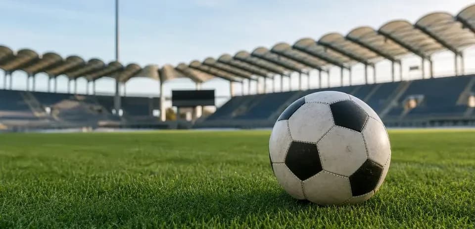 Balón de fútbol sobre césped en estadio vacío