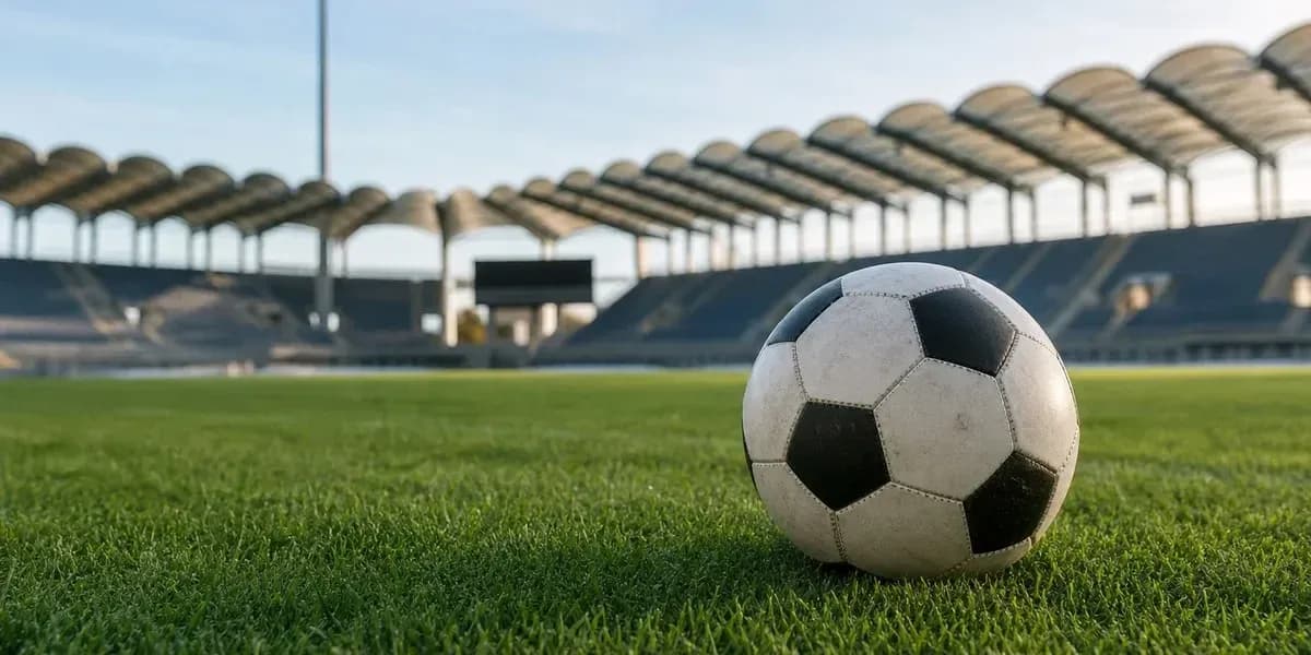 Balón de fútbol sobre césped en estadio vacío